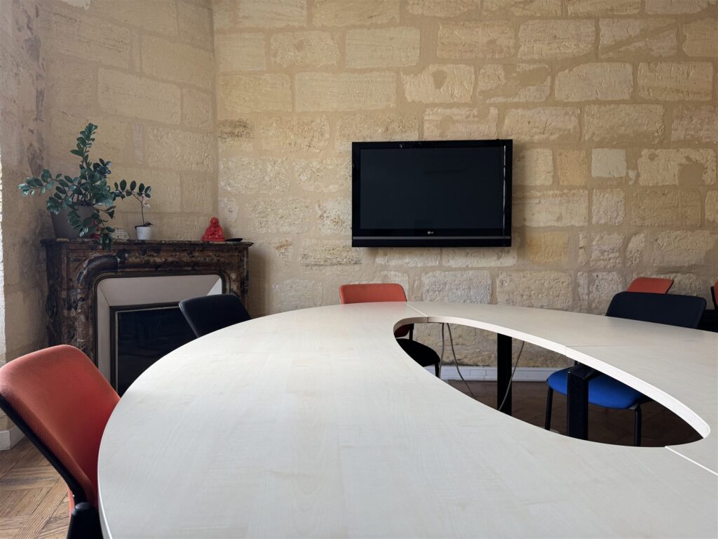 Salle de réunion avec écran et murs en pierre, coworking WorkingPlace à deux pas du Bouscat