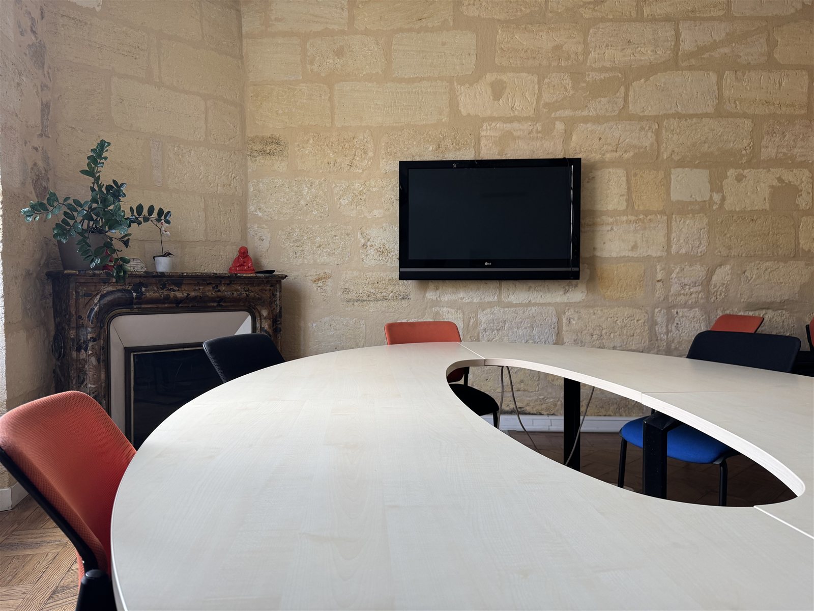Salle de réunion table ovale et écran, murs en pierre bordelaise