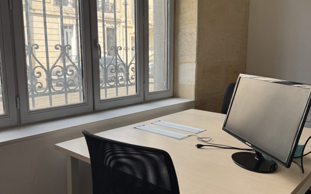 Bureau équipé avec écran et vue sur une façade bordelaise, coworking WorkingPlace